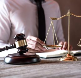 Legal law, advice and justice concept, Professional male lawyers working on courtroom sitting at the table and signing papers with gavel and Scales of justice.